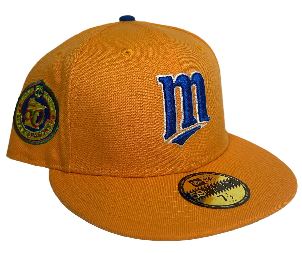 New Era 59FIFTY Minnesota Twins fitted hat features a vibrant orange and yellow colorway with a bold blue "M" logo and a commemorative side patch.