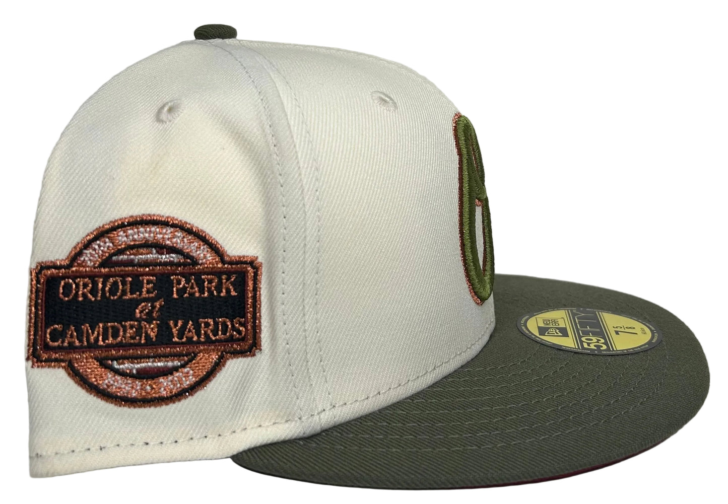 New Era 59Fifty fitted hat for the Baltimore Orioles, featuring an off-white crown, olive green visor, and a 20th-anniversary patch for Oriole Park at Camden Yards.