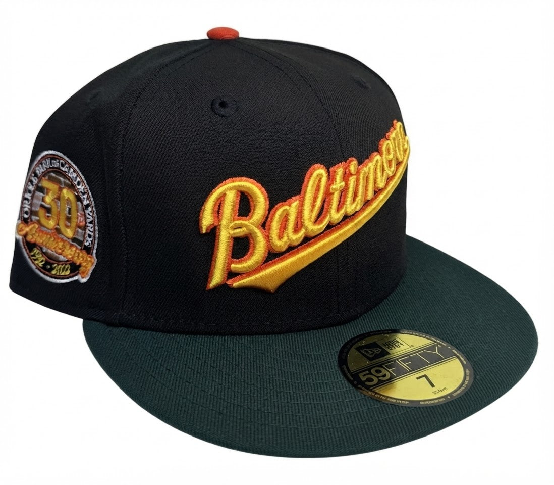 New Era Baltimore Orioles 30th Anniversary Community Edition 59FIFTY fitted cap features a black crown, dark green brim, and a retro "Baltimore" script embroidery.
