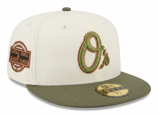 New Era 59Fifty fitted hat for the Baltimore Orioles, featuring an off-white crown, olive green visor, and a 20th-anniversary patch for Oriole Park at Camden Yards.
